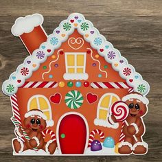 a gingerbread house cutout on a wooden surface with candy canes and candies