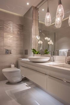 a bathroom with a white toilet sitting next to a sink and a large mirror on the wall