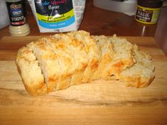 a loaf of bread sitting on top of a wooden cutting board next to bottles of mayonnaise