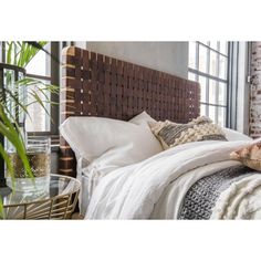 a bed with white linens and pillows in a bedroom next to a brick wall