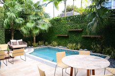 a small backyard with a pool and patio furniture set up around an outdoor dining table