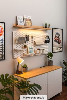 there is a desk with some plants on it and pictures above the desk, along with two bookshelves