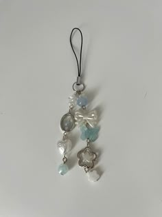 an ornament hanging from a cord on a white surface with beads and charms