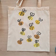 a white bag with yellow and black bees on it next to some blue yarn balls