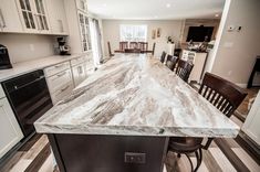 a large kitchen island in the middle of a dining room with chairs and an oven