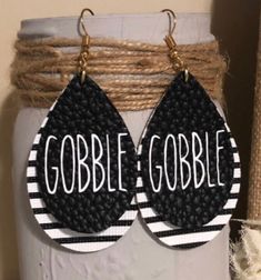 black and white earrings with the word gobble gobble written on them hanging from a rope