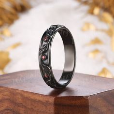 a black ring with red stones sitting on top of a wooden stand