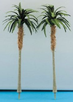 two fake palm trees are shown in front of a white wall with blue flooring