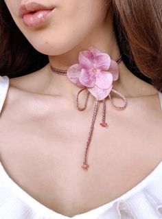 a woman wearing a necklace with pink flowers on it