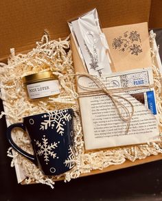 an open box with some items in it and a coffee cup on the table next to it