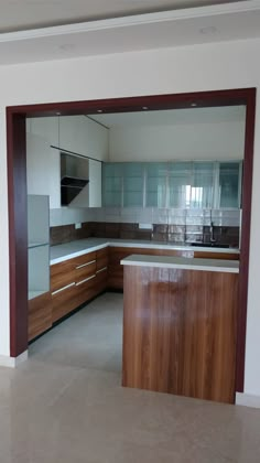 an empty kitchen with wooden cabinets and marble counter tops, is seen from the doorway