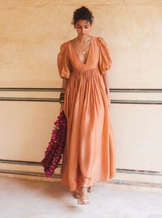 Introducing the peachy orange maxi dress, crafted from soft silk organza fabric for a luxurious feel. With its deep v neckline and fully voluminous sleeves, this dress exudes elegance and charm. Adorned with floral motif cutwork embroidery, it's the perfect choice for a fancy brunch date, adding a touch of sophistication to your ensemble. Brown Gown, Silk Organza Fabric, Fancy Brunch, Fusion Wear, Trendy Outfits Indian, Outfits Indian, Orange Maxi Dress, Peachy Orange, Voluminous Sleeves