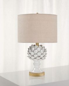 a lamp that is sitting on top of a table in front of a white curtain