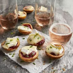 small appetizers are sitting on a table next to wine glasses and napkins