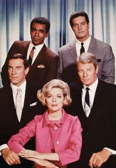 a group of men and women in suits posing for a photo with curtains behind them