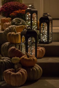 pumpkins and lanterns sitting on the steps in front of a house