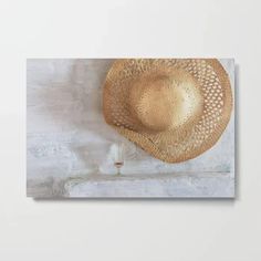 a straw hat hanging on the wall next to a wine glass with a cork in it