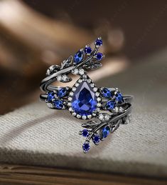 an elegant ring with blue stones and leaves on the side, sitting on top of a book