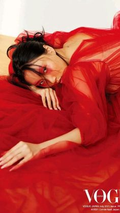 a woman laying on top of a bed in a red dress