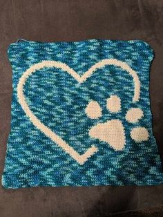 a knitted pillow with a dog's paw and heart on it