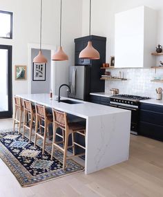 a kitchen with black cabinets, white countertops and an island that has chairs around it