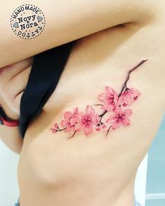 a woman's stomach with pink flowers tattooed on her side and the bottom part of her body