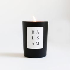 a black candle with the words ba is am on it's side and a white background