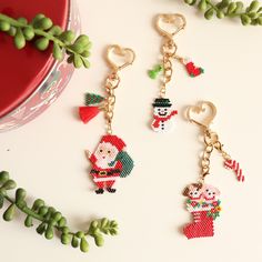 three christmas themed keychains with santa and snowman charms hanging from them on a white surface