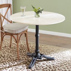 a white table with two chairs and a vase on it in front of a green wall