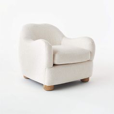 a white chair sitting on top of a white floor next to a wooden legrest