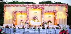 an outdoor stage decorated with flowers and greenery for a wedding or reception ceremony in the evening