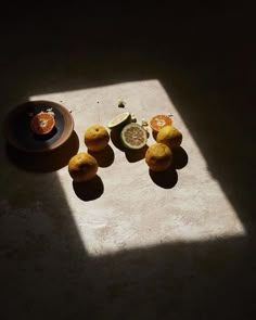 some fruit is sitting on a table in the sun, with one half eaten orange and two whole kiwis