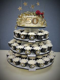 a tiered cake with cupcakes on it and a sign that says 50