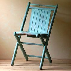 a green wooden chair sitting on top of a hard wood floor next to a wall