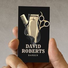 a person holding up a business card with scissors and combs on it that says david roberts barber