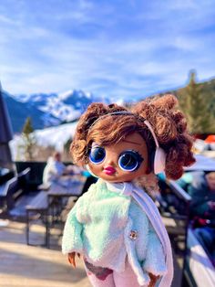 a close up of a doll with big blue eyes and brown hair wearing a white jacket