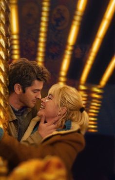 a man and woman standing next to each other in front of a merry go round