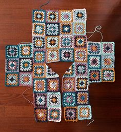 a crocheted square is sitting on a wooden table