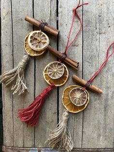 three orange slices and cinnamon sticks are arranged on a piece of wood with twine