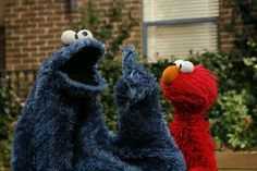 two sesame street characters standing next to each other