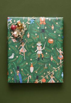 a green wrapping paper with christmas decorations on it and an ornament hanging from the top