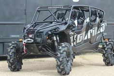 a large four - wheeled vehicle parked in front of a black trailer with the door open