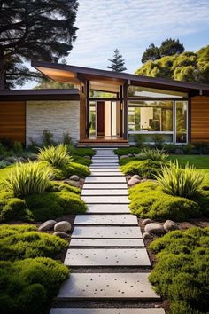 a modern house in the middle of a garden with grass and bushes on either side