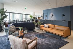 an office lobby with couches, chairs and potted plants on the wall behind them