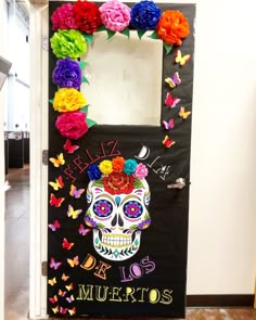 a door decorated with colorful paper flowers and a skull in the center that says los muertos