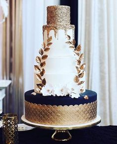 a three tiered wedding cake with gold leaf decorations on the top and bottom layer