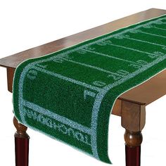 a green table runner with white writing on it and a wooden bench in the background