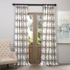 a living room with a chair, window and white curtains in front of a wooden door