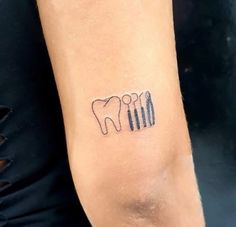 a person with a small tattoo on their arm that has tooth and dental instruments in it