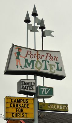 a motel sign with many different signs attached to it's sides and the words peter pan motel on top